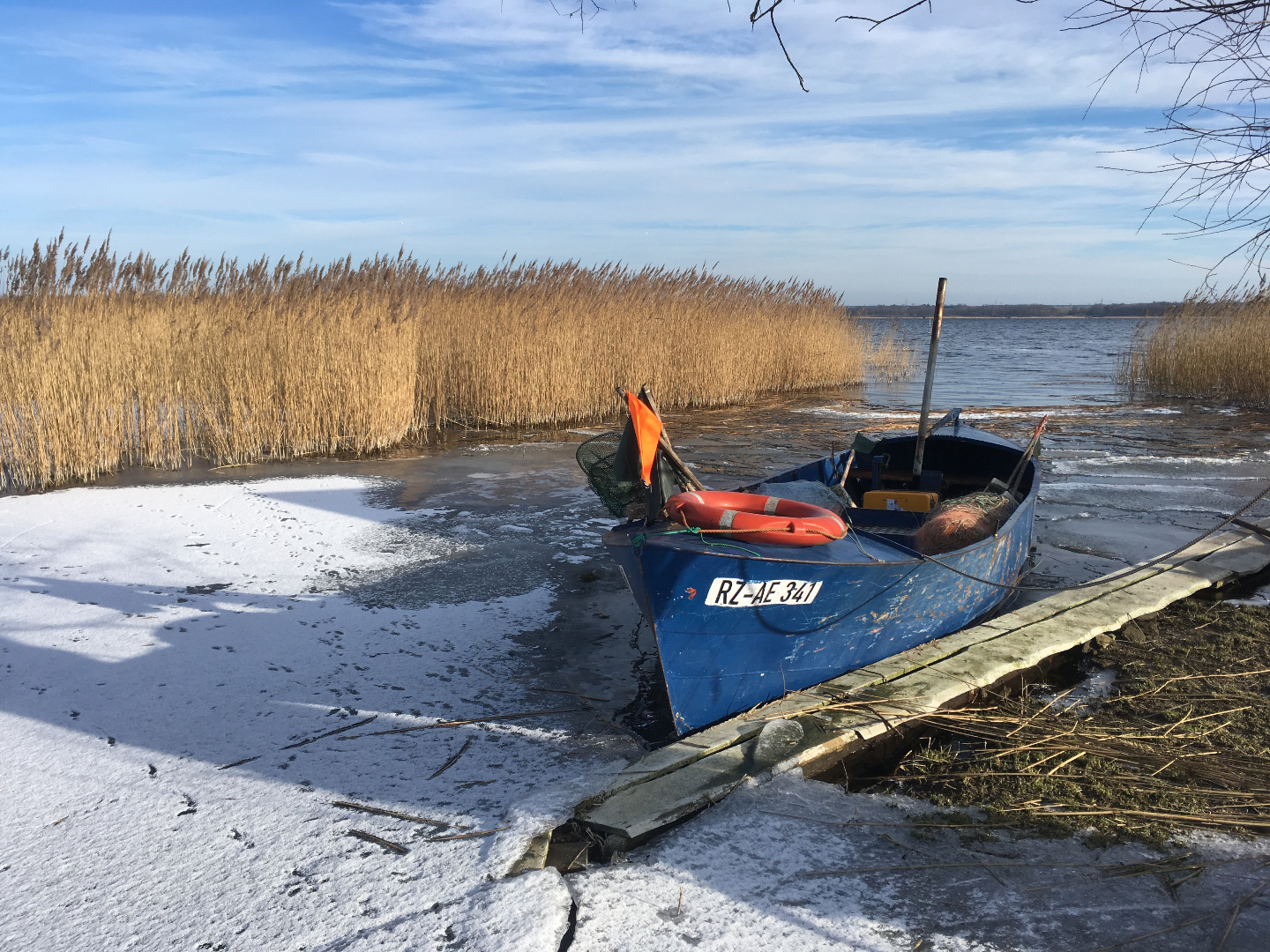 Blaues Fischerboot RZ-AE 341 auf gefrorenem See im Winter
